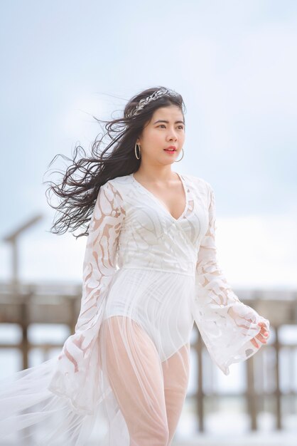 Schöne Frau im weißen Kleid am Strand