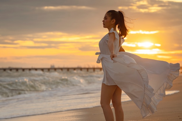 Schöne Frau im weißen Kleid am Strand