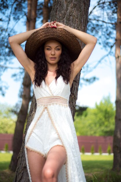 Schöne Frau im weißen Sommerkleid und Strohhut im Garten