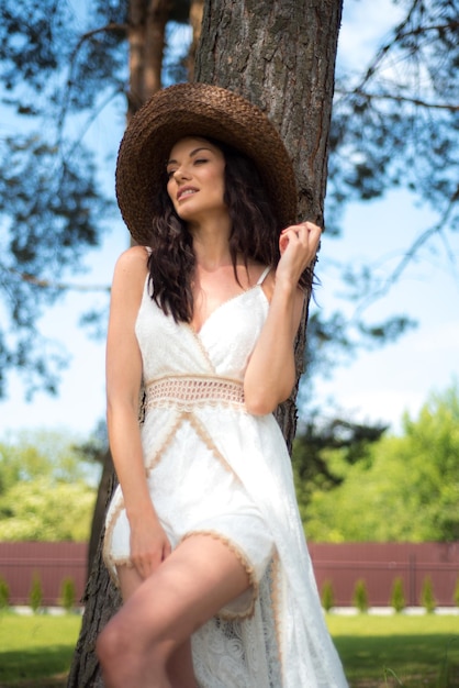 Schöne Frau im weißen Sommerkleid und Strohhut im Garten