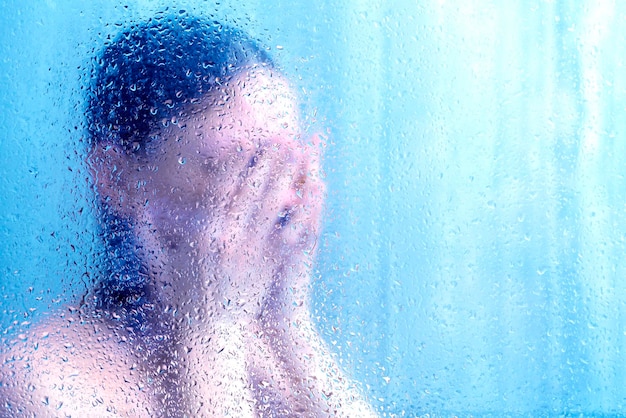 Foto schöne frau in der dusche hinter glas mit blauen tropfen