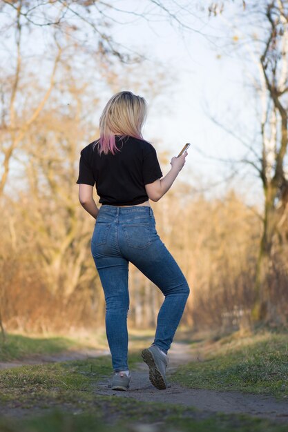 Schöne Frau in der Herbstlandschaft. Junger Hipster, der Handy hält.