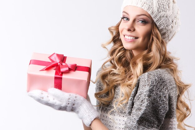 Schöne Frau in der Winterkleidung mit Weihnachtsgeschenken auf weißem Hintergrund.