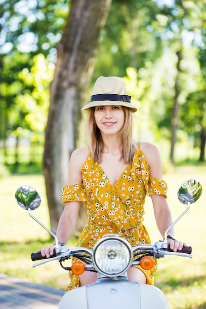 Schöne Frau in einem gelben Kleid mit einem Retro-Roller