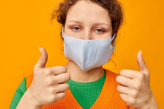 Schöne Frau in einem gelben T-Shirt, medizinischer Maskenschutz, unbeschnittene Ansicht unverändert