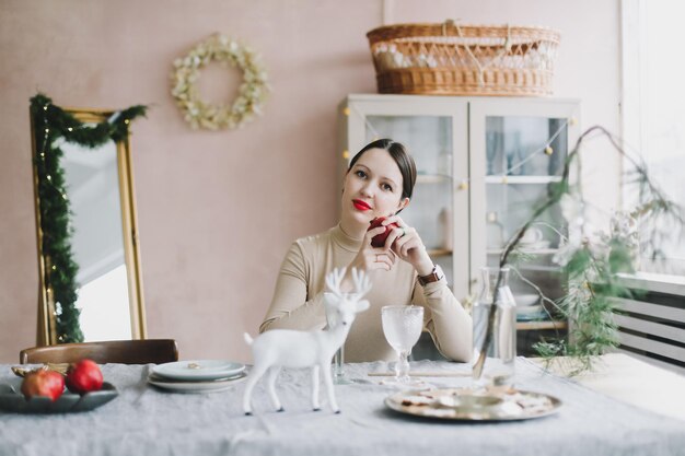 Schöne Frau in einem gemütlichen Interieur, das für Neujahrs- und Weihnachtsfeiern dekoriert ist Frauenporträt auf dem Hintergrund eines Weihnachtsbaums in einem Wohninterieur und festlicher Atmosphäre