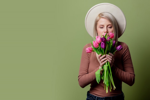 Schöne Frau in einem Hut mit Tulpenblumenstrauß