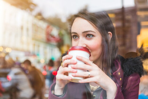 Schöne Frau in einem Kaffee, der eine Manschette des Tees anhält