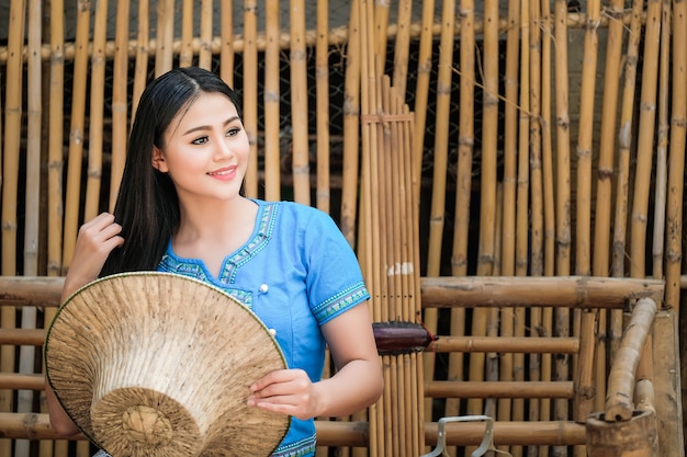 Schöne Frau in einem traditionellen thailändischen Kleid, blau in einer rustikalen thailändischen Atmosphäre