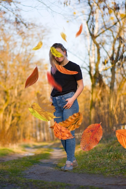 Schöne Frau in Herbstlandschaft mit Bäumen in gelb-orange-roten Farben