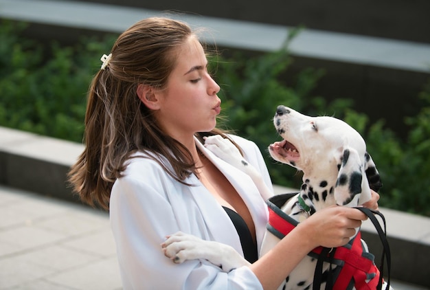 Schöne Frau in modischer Sommerfrühlingskleidung, die mit Hund im Freien spazieren geht