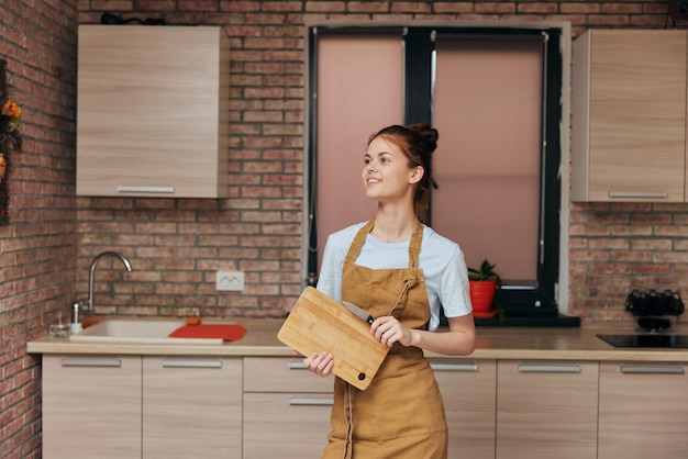 Schöne Frau in Schürze, Schneidebrett mit Messer in der Küche, Hausarbeit, Haushaltskonzept, hochwertiges Foto