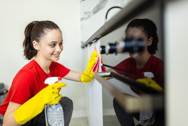 Schöne Frau in Schutzhandschuhen, die Küchenofen in der Küche säubert