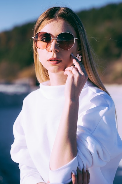 Schöne Frau in Sonnenbrille und weißer Kleidung