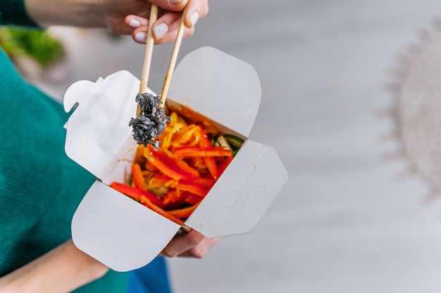 Schöne Frau isst asiatisches Fast Food aus der Takeaway-Box. Leckere Wok-Nudeln.