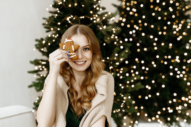 schöne Frau lächelt vor dem Hintergrund eines Weihnachtsbaumes zu Hause