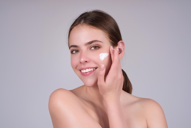 Schöne Frau legt Feuchtigkeitscreme auf ihr Gesicht Schönheitskonzept Hautpflege und verwöhnen Anti-Aging-Creme Junges Modell legt Creme auf Mädchen legt Kosmetikcreme auf das Gesicht