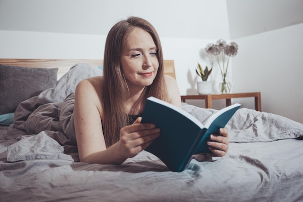 Schöne Frau liest auf einem bequemen Bett