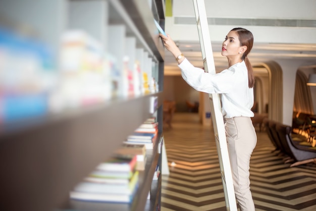 Schöne Frau liest Bücher in der Bibliothek