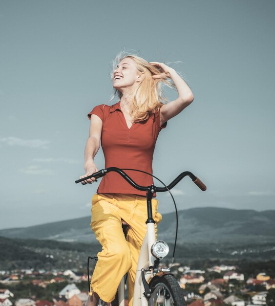 Schöne Frau machte eine Pause, während sie an einem guten sonnigen Tag mit ihrem Vintage-Fahrrad fuhr Sommerferien und unbeschwerte Zeit Hübsche blonde Frau genießt ihren Spaziergang mit dem Fahrrad Radfahren Konzept