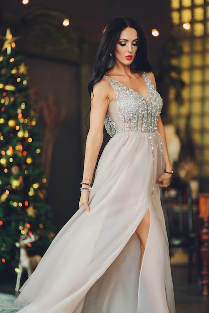Schöne Frau Mädchen im Neujahrsstudio posiert Foto Neujahrs-Fotosession Schönes Mädchen in einem luxuriösen Kleid mit schlanken Beinen Weihnachts-Winter-Glückskonzept