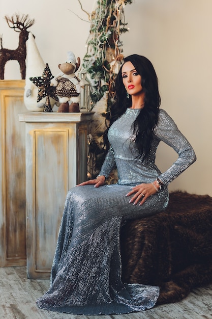 Schöne Frau Mädchen in Neujahrsstudio posiert, Foto Neujahr Fotosession. Schönes Mädchen in einem luxuriösen Kleid mit schlanken Beinen. Weihnachts-, Winter-, Glückskonzept.