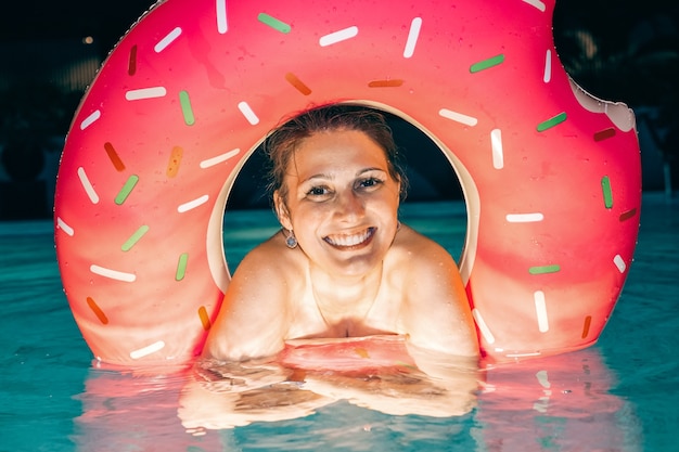 Schöne Frau mit aufblasbarem Ring im Hotelpool nachts