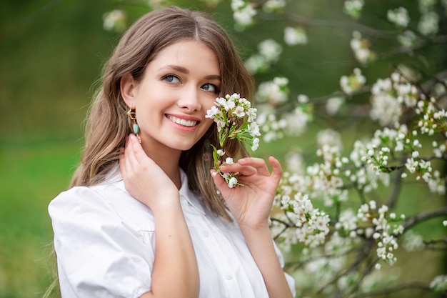 Schöne Frau mit blühenden Frühlingsblumen auf einem Baum.