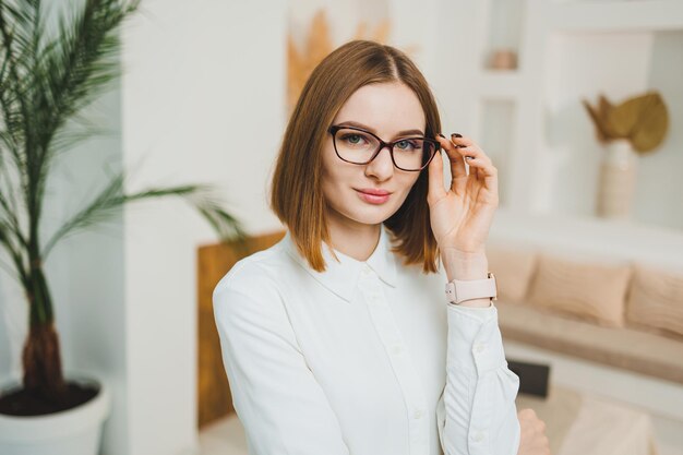 Foto schöne frau mit brille im offenen raum, im coworking-büro, entspannt, entspannt und arbeitet online, trägt weißes t-shirt und jeans.