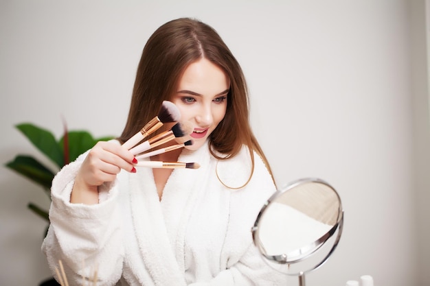 Schöne Frau mit Bürste für das tägliche Make-up im Badezimmer