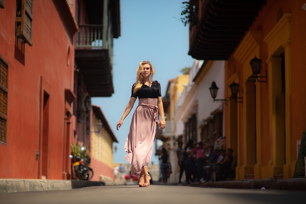 Schöne Frau mit dem langen Kleid, das allein an den bunten Straßen der kolonial ummauerten Stadt Cartagena geht. Kolumbien.