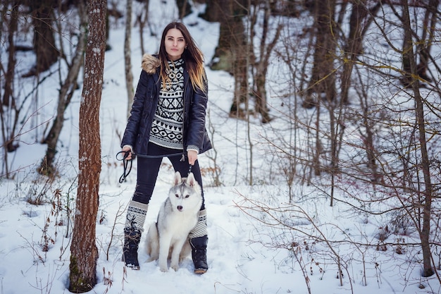 Schöne Frau mit einem Husky, der im Winter aufwirft