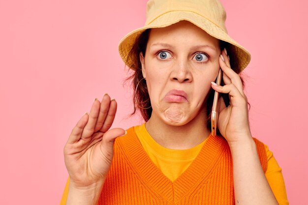 Schöne Frau mit einem Telefon in der Hand Grimasse Ohrringe Kappe Mode isolierte Hintergründe unverändert