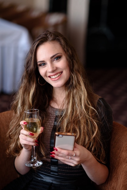 Schöne Frau mit einem Telefon und einem Glas Champagner