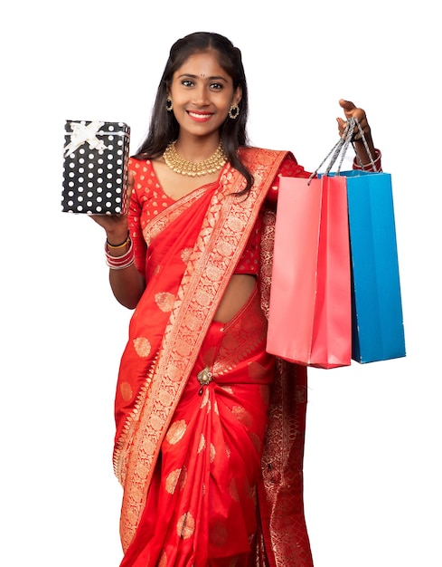 Schöne Frau mit Einkaufstüten und Geschenkbox auf weißem Hintergrund