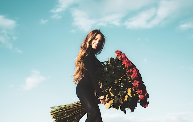 Schöne frau mit frühlingsblühenden rosenblumen feiern valentinstag romantische geschenke und valentinstag