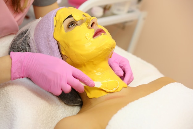 Schöne Frau mit Gesichtsmaske am Schönheitssalon.