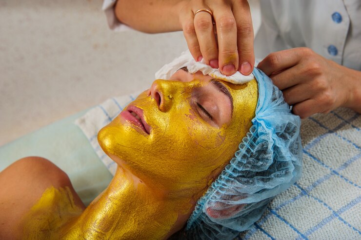 Schöne Frau mit goldener Gesichtsmaske im Schönheitssalon