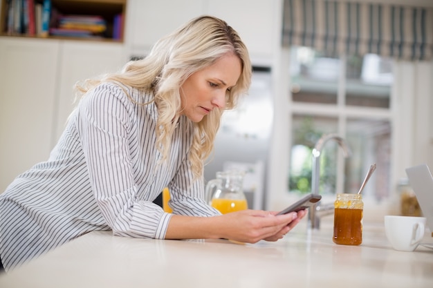 Schöne Frau mit Handy in der Küche