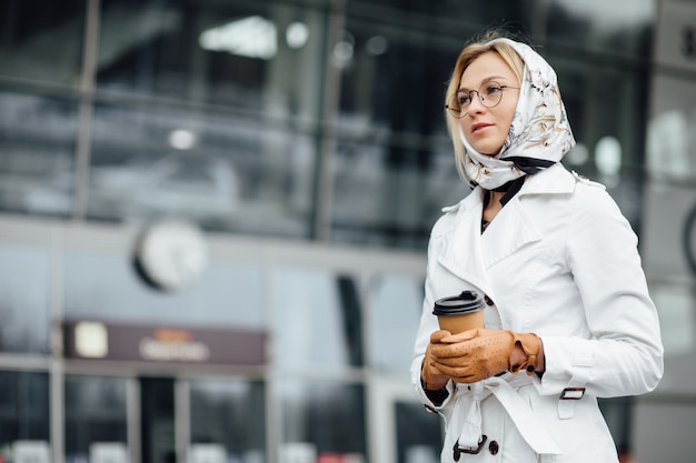 Schöne Frau mit Kaffeetasse nahe Bürogebäude.