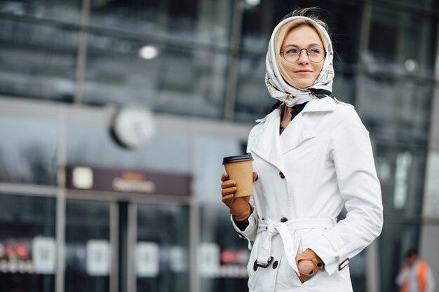 Schöne Frau mit Kaffeetasse nahe Bürogebäude.