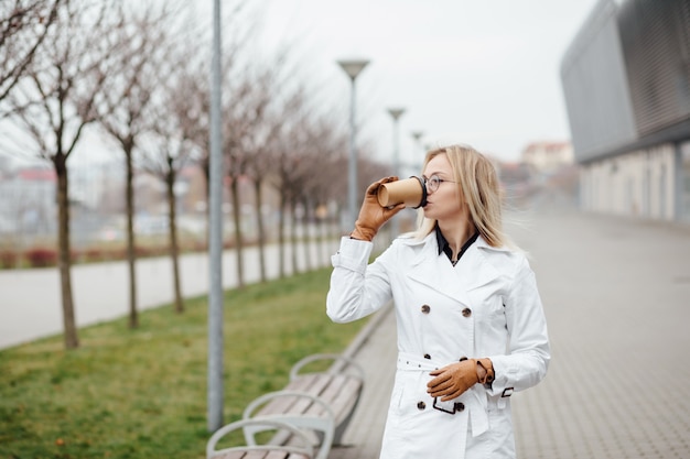 Schöne Frau mit Kaffeetasse nahe Bürogebäude.