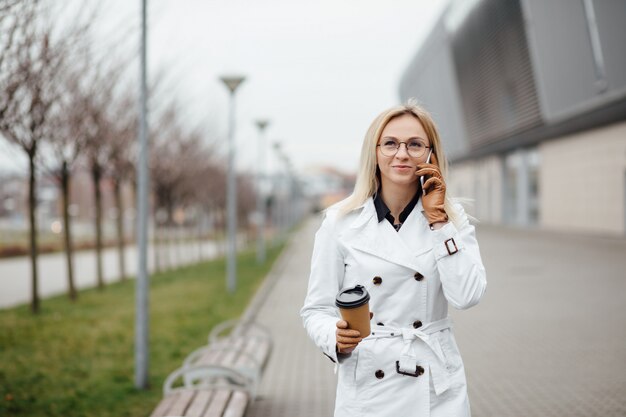 Schöne Frau mit Kaffeetasse nahe Bürogebäude.