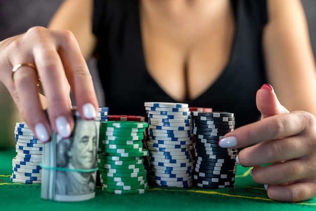 Schöne Frau mit Karten in ihren Händen macht eine Wette und gewinnt Dollar für einen erfolgreichen Wettgewinn beim Poker-Glücksspiel