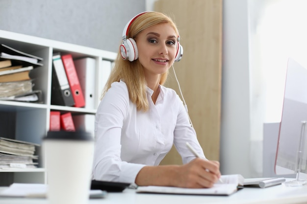 Schöne Frau mit Kopfhörern am Arbeitsplatz im Büro