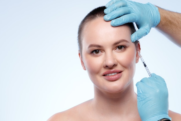 Schöne Frau mit kurzen Haaren bekommt eine Schönheitsspritze ins Gesicht