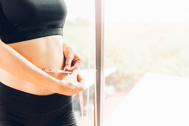 Foto schöne frau mit maßband taille, ihr körper ist nach dem training im fitnessstudio schlank