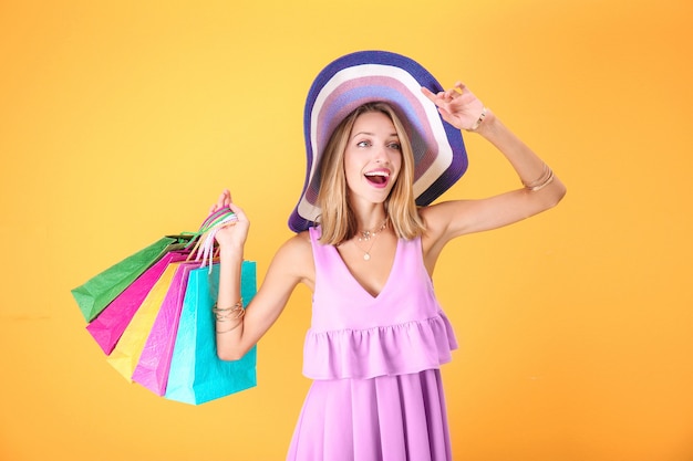 Schöne Frau mit Papiertüten auf gelb