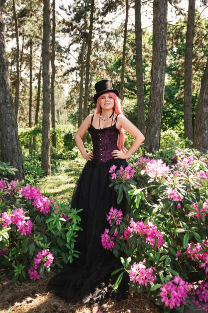 Foto schöne frau mit rosa haaren, zylinder und langem schwarzen abendkleid mit korsett