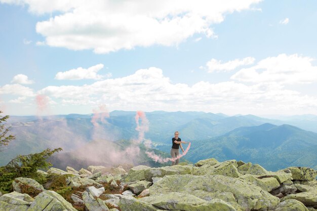 Schöne Frau mit rotem Rauch an der Spitze des Berges und bewölkten Himmelhintergrund